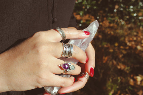 sterling silver amethyst jewelry on the hands of a boho girl holding an amethyst crystal